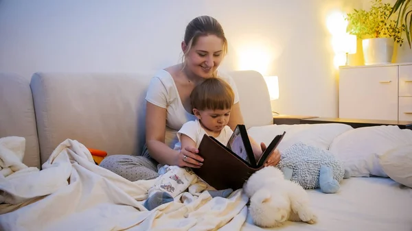 Bela jovem mãe lendo história de dormir para seu filho criança — Fotografia de Stock