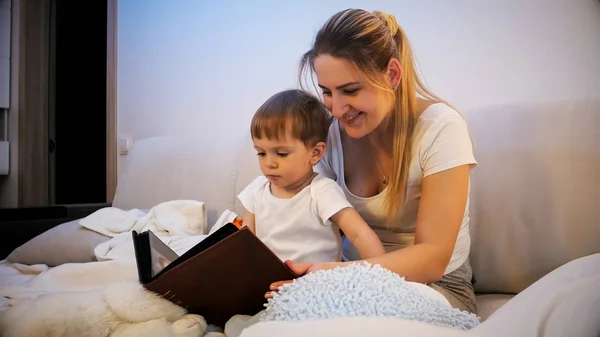 Retrato de bela mãe lendo grande livro velho para seu filho criança antes de dormir — Fotografia de Stock