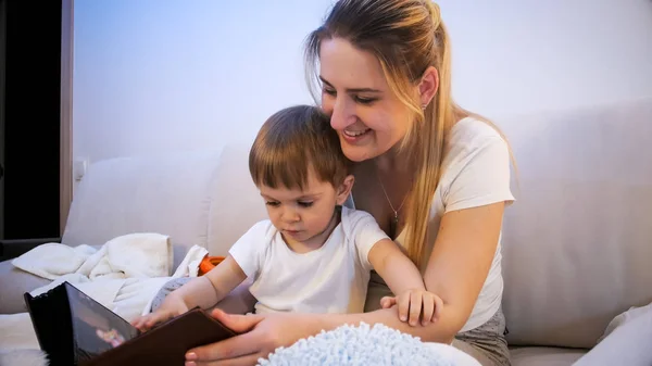Portrait of smiling young mother with her toddler boy reading big old story book — Stock Photo, Image