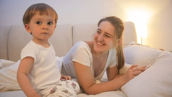 Retrato de una joven feliz acostada en la cama con su hijo pequeño —  Fotos de Stock