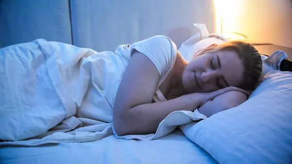 Портрет спящей молодой женщины в спальне с прикроватной лампой — стоковое фото
