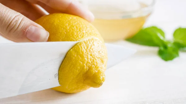 新鮮なレモンをナイフで切断の手のクローズ アップ画像 — ストック写真