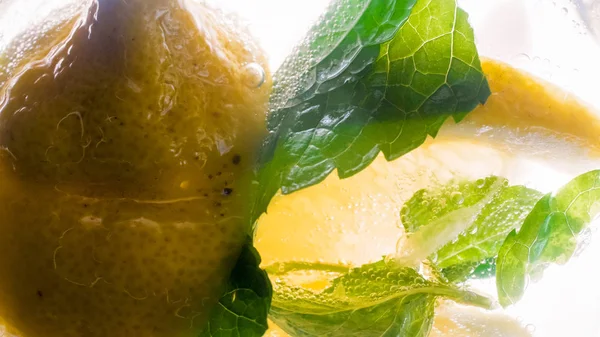 Macro image of mint leaves and lemon slice in glass of lemonade — Stock Photo, Image