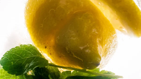 Макроизображение ломтика лимона и мяты, оставленных в холодной газированной воде — стоковое фото