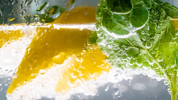 Foto de cerca de burbujas de aire en rodajas de limón y menta y vaso de limonada — Foto de Stock