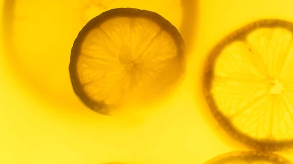 Imagen retroiluminada de primer plano de rebanada de naranja flotando en el jugo — Foto de Stock