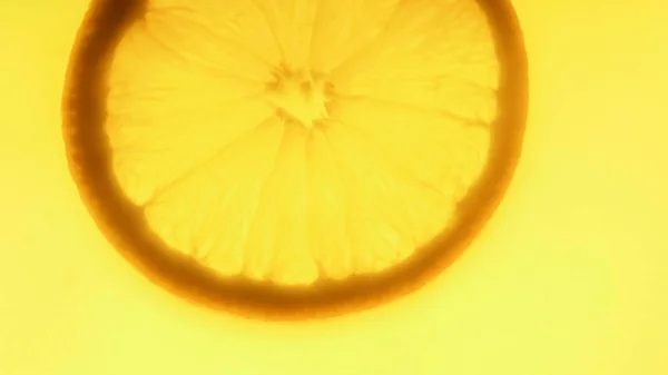 Imagen macro de rebanada de naranja recién cortada flotando en jugo de naranja — Foto de Stock