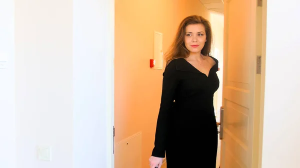 Portrait of beautiful elegant businesswoman in black dress enetering hotel room — Stock Photo, Image