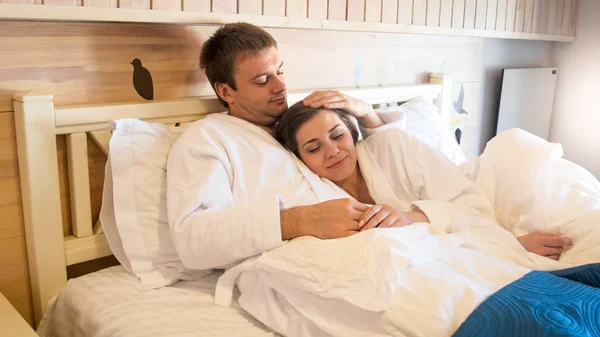 Retrato de jovem bonito abraçando sua esposa na cama no hotel — Fotografia de Stock