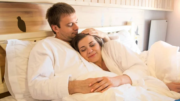 Retrato de belo jovem casal deitado na cama e abraçando — Fotografia de Stock