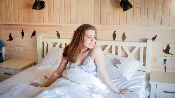 Portret obudzić uśmiechający się kobieta siedzi na łóżku w pokoju hotelowym — Zdjęcie stockowe