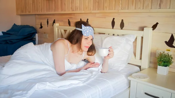 Retrato de jovem mulher tomando café na cama de manhã — Fotografia de Stock