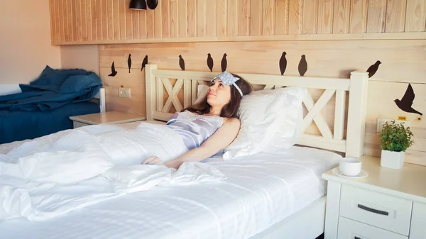 Krásná mladá žena probuzení na ranní a ležící v posteli — Stock fotografie
