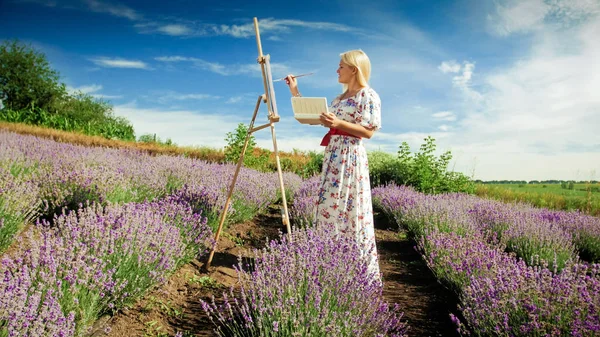 Mujer rubia joven dibujo floreciendo campo de lavanda por la mañana — Foto de Stock