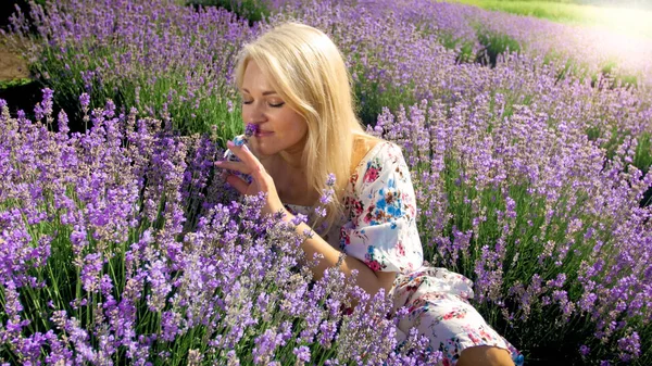 Retrato de cerca de una joven rubia oliendo flores de lavanda en el campo — Foto de Stock