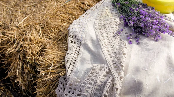 Closeup still life of linen tablecloth and lavender flowers on hay stack — Stock Photo, Image