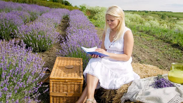 Bella donna sorridente seduta su pila di fieno e libro di lettura — Foto Stock