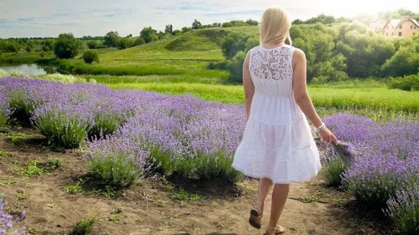 Νεαρή ξανθιά γυναίκα στο λευκό φόρεμα περπάτημα στο πεδίο λεβάντα — Φωτογραφία Αρχείου