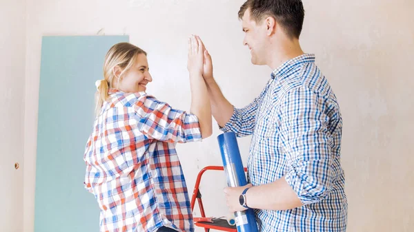 Happy young couple making renovation at home and giving five to each other — Stock Photo, Image