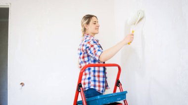 Yenileme yapıyor ve boyama duvarları güzel sarışın kadın