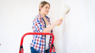 Evde tadilat yapıyor rulo boya ile güzel genç kadın