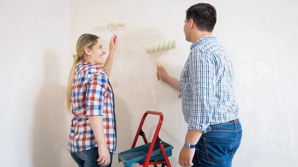 Lächelndes junges Paar streicht Wände in neuem Haus — Stockfoto