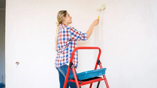 Портрет красивой молодой женщины, рисующей стены в своем новом доме — стоковое фото