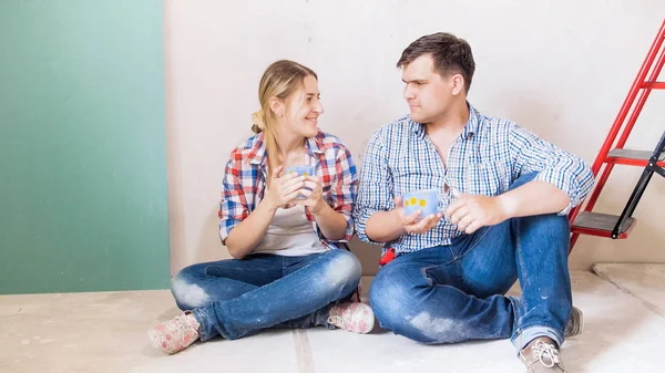 Mladý pár sedící na podlaze doma probíhá rekonstrukce a pití kávy — Stock fotografie