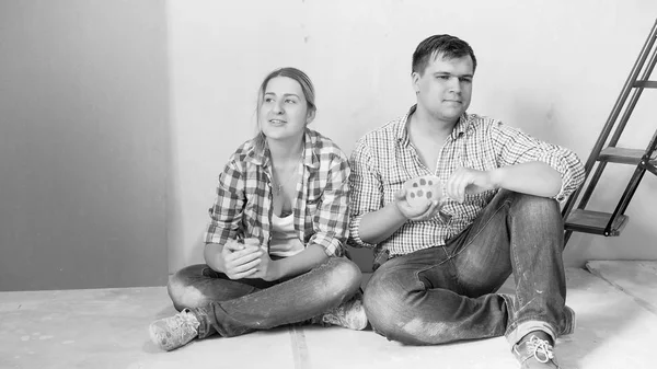Svartvit bild av unga paret sitter på golvet efter renovering på huset — Stockfoto
