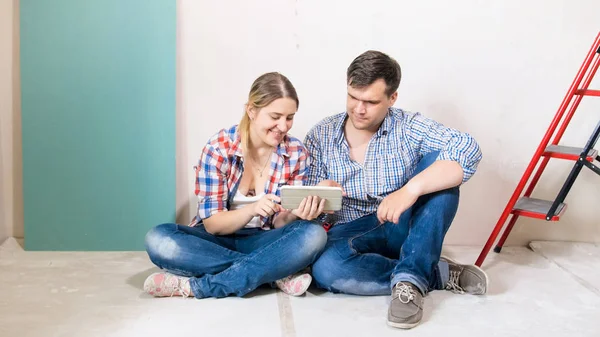 Unga leende familjen använda digitala surfplatta i hus under renovering — Stockfoto