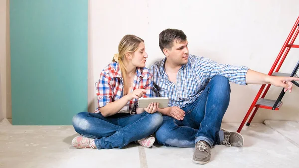 Jeune couple choisissant des lieux pour de nouveaux meubles dans leur maison en rénovation — Photo