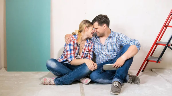 Счастливая улыбающаяся пара обнимается на полу нового дома под ремонтом — стоковое фото
