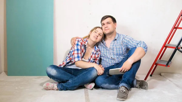 Hermosa pareja amorosa abrazándose en el piso de su nueva casa bajo renovación —  Fotos de Stock