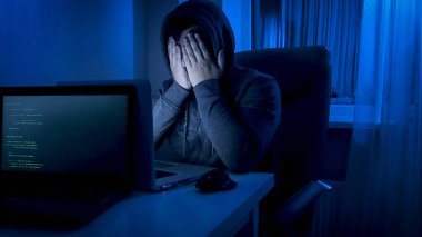 Genç prgrammer veya saldırgan çalışma gece ve yüzünü elleri ile kapanış başlıklı portresi