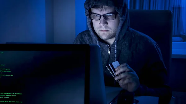 Portret młody mężczyzna cyber karnego kradzież pieniędzy z karty kredytowej na laptopie — Zdjęcie stockowe