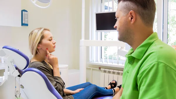 Portrait de belle jeune femme montrant la dent douloureuse à son dentiste — Photo