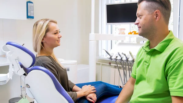 Vackra leende kvinna som sitter i tandvårdsklinik och leende till hennes tandläkare — Stockfoto
