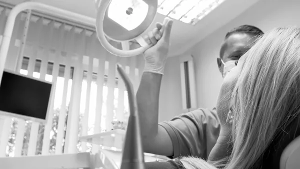 Black and white closeup image of dentist adjusting lamp — Stock Photo, Image