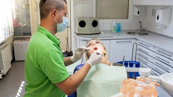 Jovem mulher visitando consultório de dentista para inspeção de dentes — Fotografia de Stock