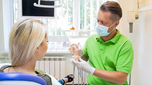 Porträtt av manliga tandläkare i skyddande mask prata med sin patient före behandlingen — Stockfoto