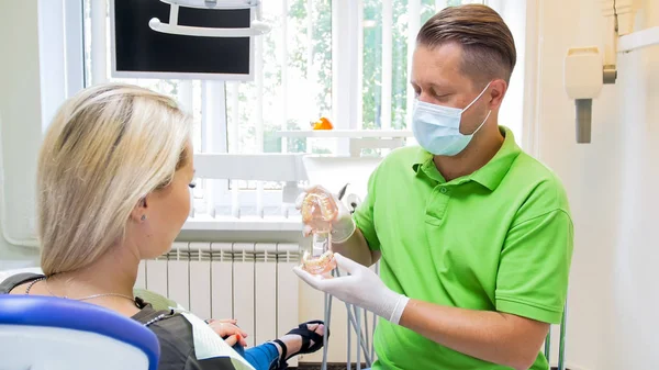 Manliga tandläkare förklarar tänder behandling att hans patient — Stockfoto