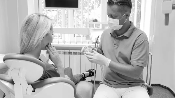 Retrato preto e branco do dentista masculino conversando com seu paciente antes do tratamento — Fotografia de Stock
