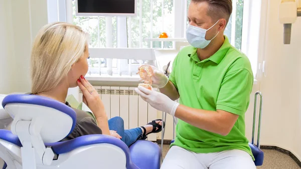 Manliga tandläkare till ung kvinna med smärta i tänderna — Stockfoto