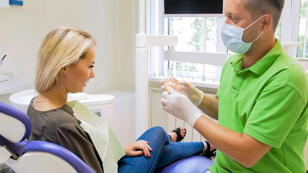 Retrato de mulher loira bonita conversando com dentista sobre mnethods de tratamento de dentes — Fotografia de Stock