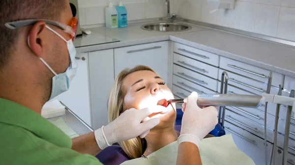 Imagem de perto do dentista usando fotopolímero e lâmpada UV para o tratamento dos dentes — Fotografia de Stock