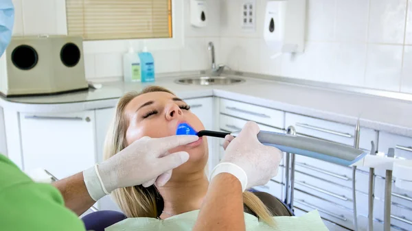 Imagem de close-up do dentista usando lâmpada ultravioleta para tratamento de dentes — Fotografia de Stock