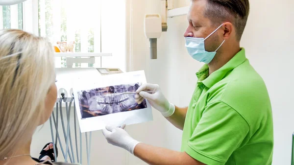 Retrato do dentista masculino que explica a imagem do raio-X ao seu paciente — Fotografia de Stock