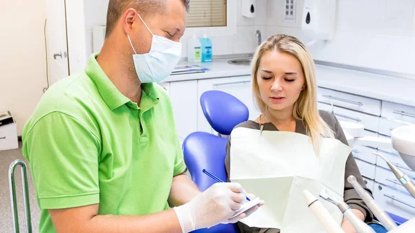 Retrato do dentista masculino que escreve a prescrição ao paciente — Fotografia de Stock