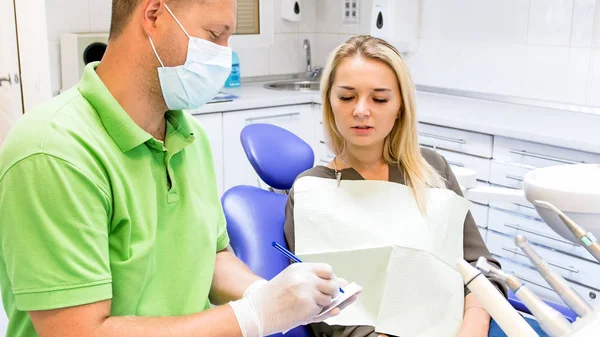 Retrato de dentista masculino que escreve prescrição em papel — Fotografia de Stock