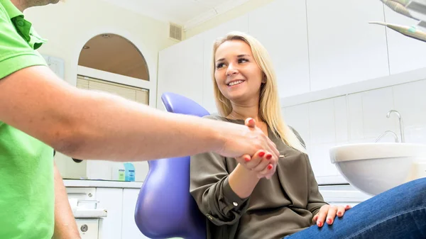 Retrato de jovem sorridente apertando as mãos com o dentista em seu escritório — Fotografia de Stock